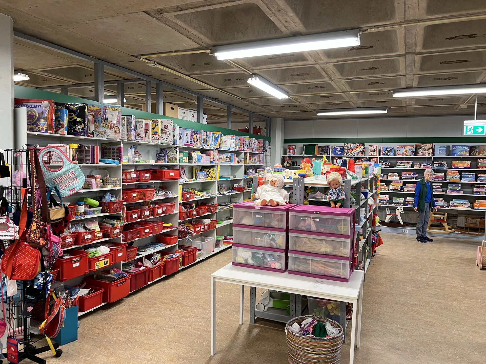 Winkelvloer met stellingen vol speelgoed, boeken en huishoudartikelen in verschillende kleuren