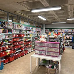 Winkelvloer met stellingen vol speelgoed, boeken en huishoudartikelen in verschillende kleuren
