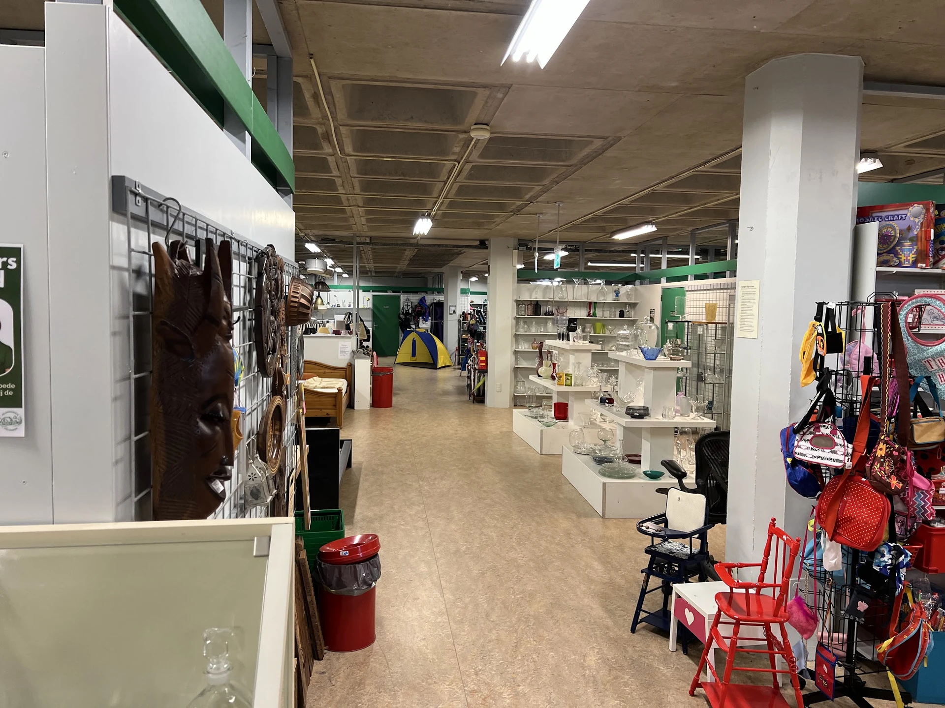 Winkelvloer van kringloopwinkel met stellingen, rekken met kleding en diverse uitgestalde spullen
