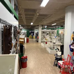 Winkelvloer van kringloopwinkel met stellingen, rekken met kleding en diverse uitgestalde spullen