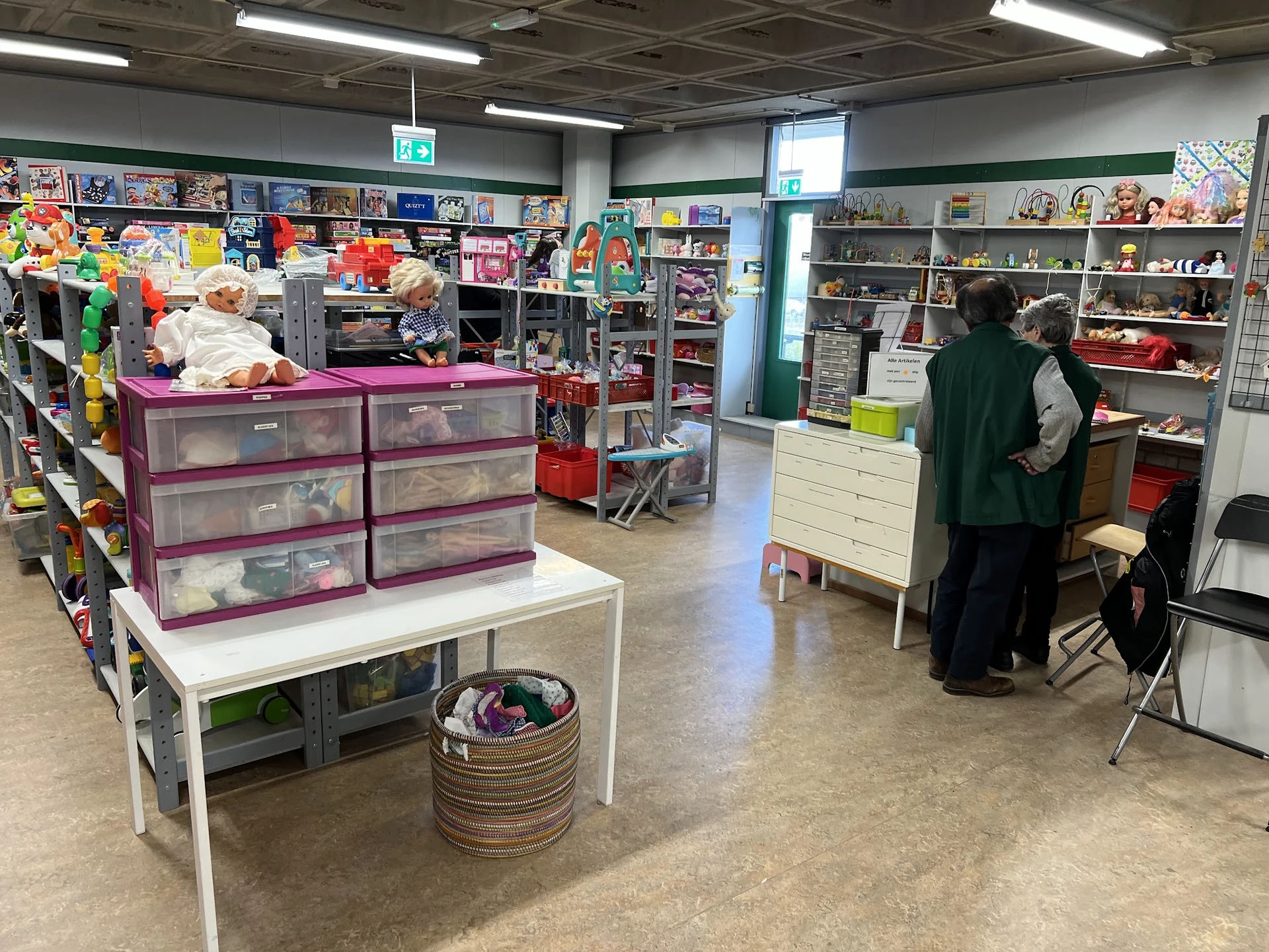 Winkelvloer met stellingen, toonbanken en spullen in een kringloopwinkel, bezoekers aan het winkelen