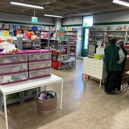 Winkelvloer met stellingen, toonbanken en spullen in een kringloopwinkel, bezoekers aan het winkelen