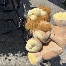 Close-up van een pluchen knuffel in de vorm van een leeuw met bruine manen en crème-kleurige buik en poten