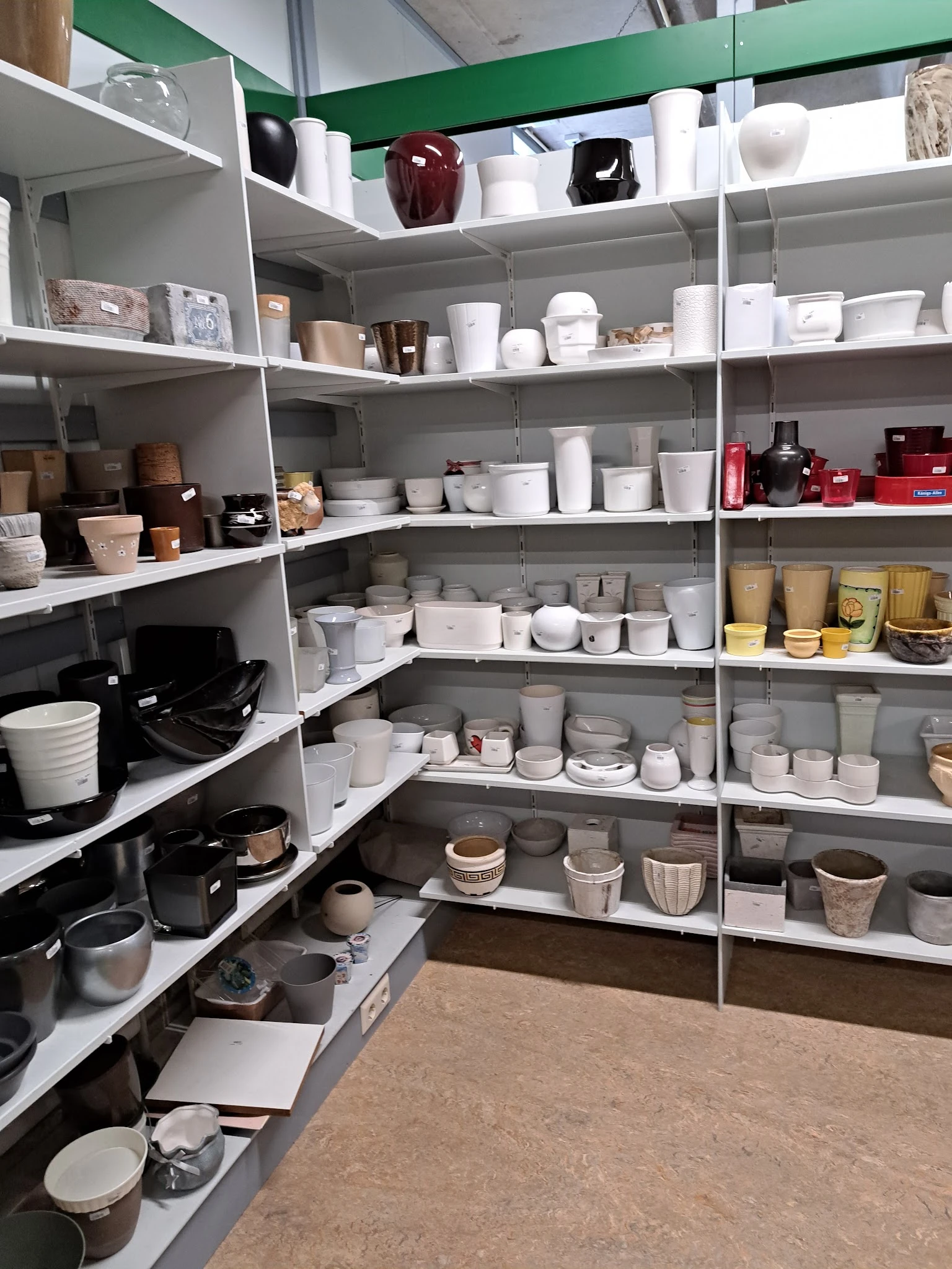Stellingen met wit serviesgoed, bekers, potten en ander huishoudelijk artikel in een kringloopwinkel