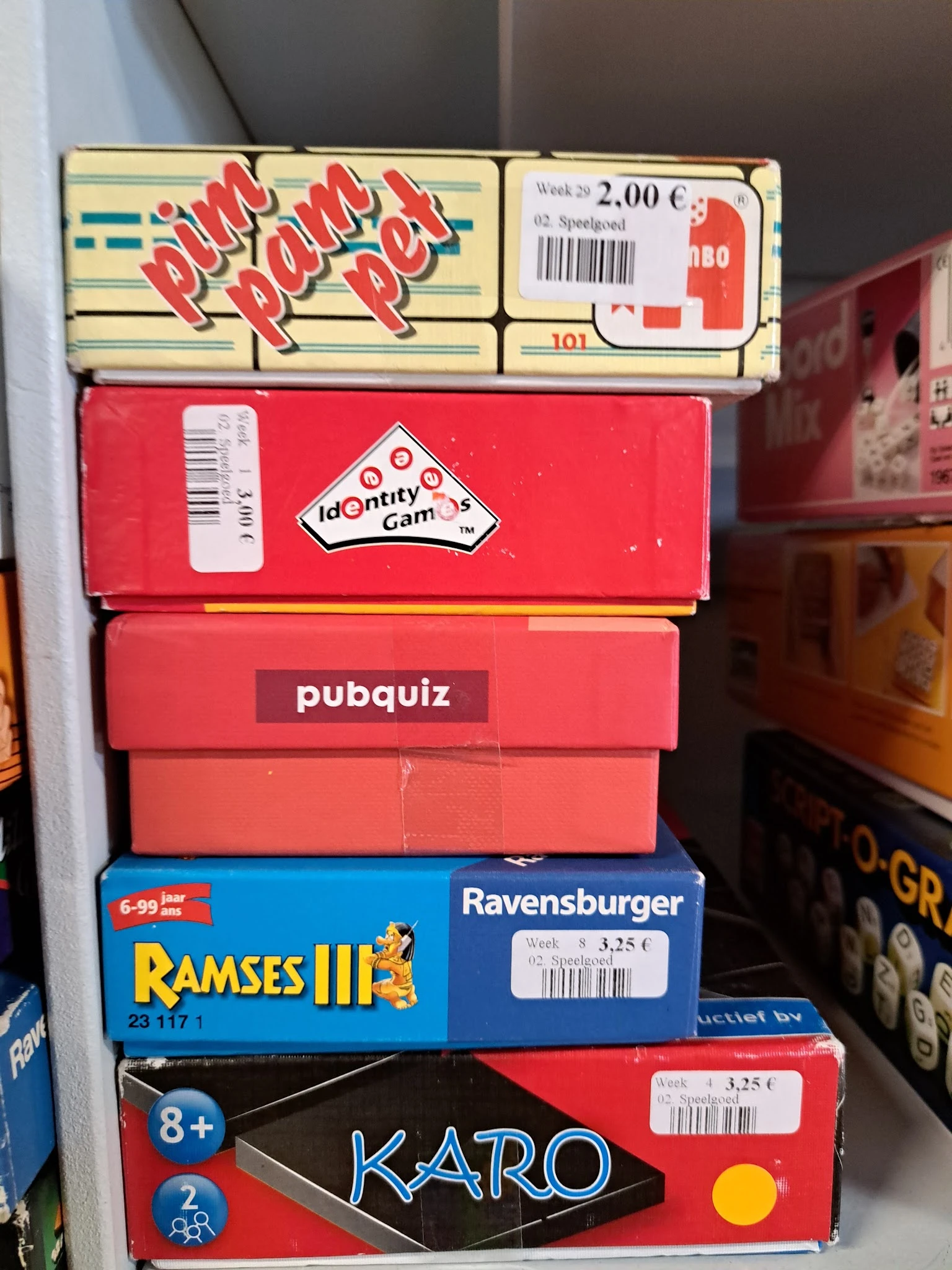 Stapel retro bordspellen en computerspellen in dozen, waaronder Identity Games, pubquiz, Ramses III en Ravensburger