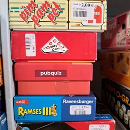 Stapel retro bordspellen en computerspellen in dozen, waaronder Identity Games, pubquiz, Ramses III en Ravensburger