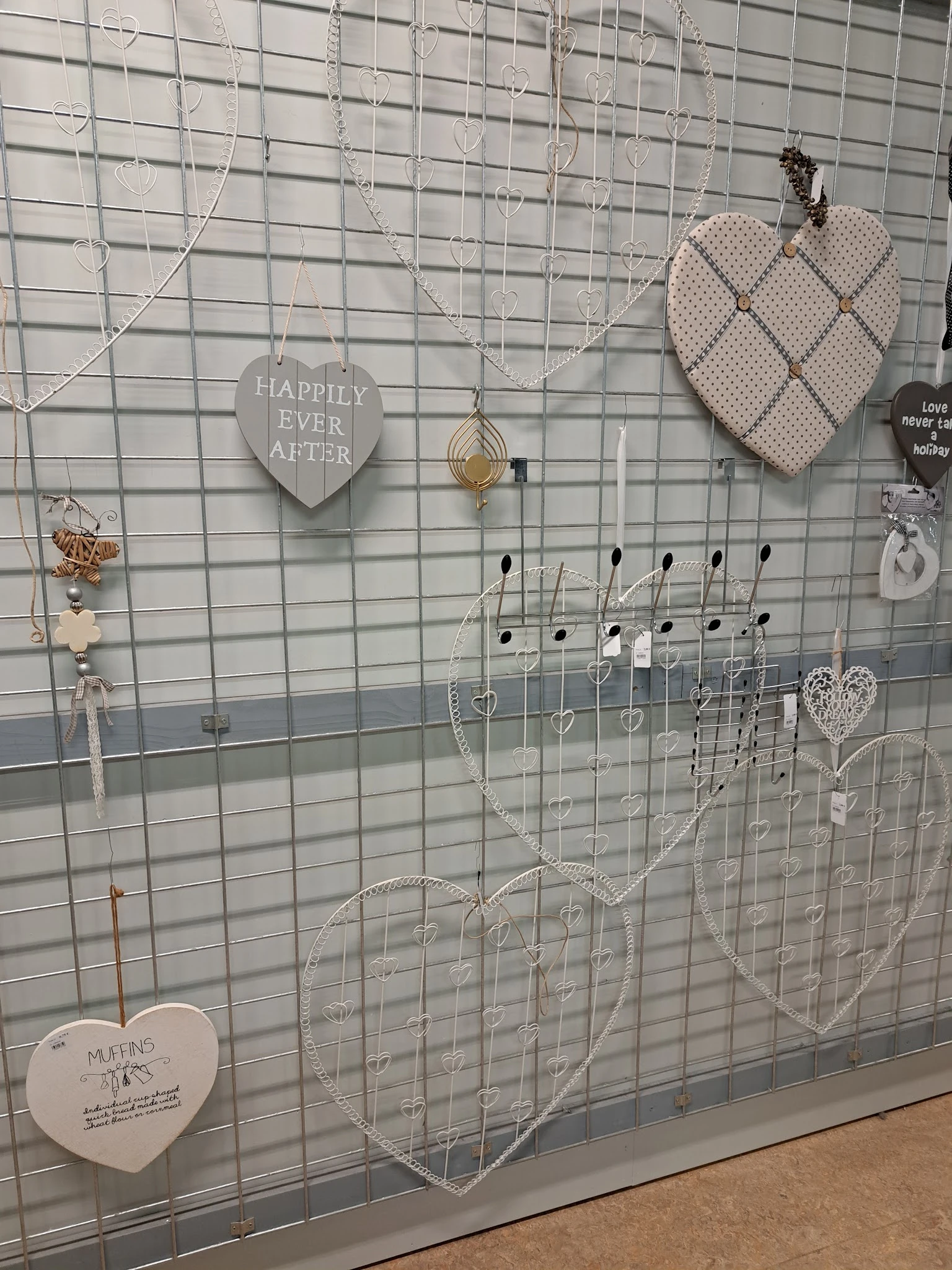 Uitgestalde sieraden en decoratieve items opgehangen aan een grijs gaas displaypaneel in de winkel