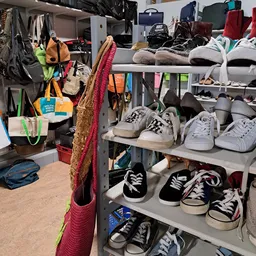 Stellingen met uitgestalde tweedehands schoenen en sneakers in verschillende kleuren en maten