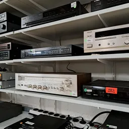 Stellingen met vintage audio-apparatuur en elektronische componenten zoals versterkers en cd-spelers