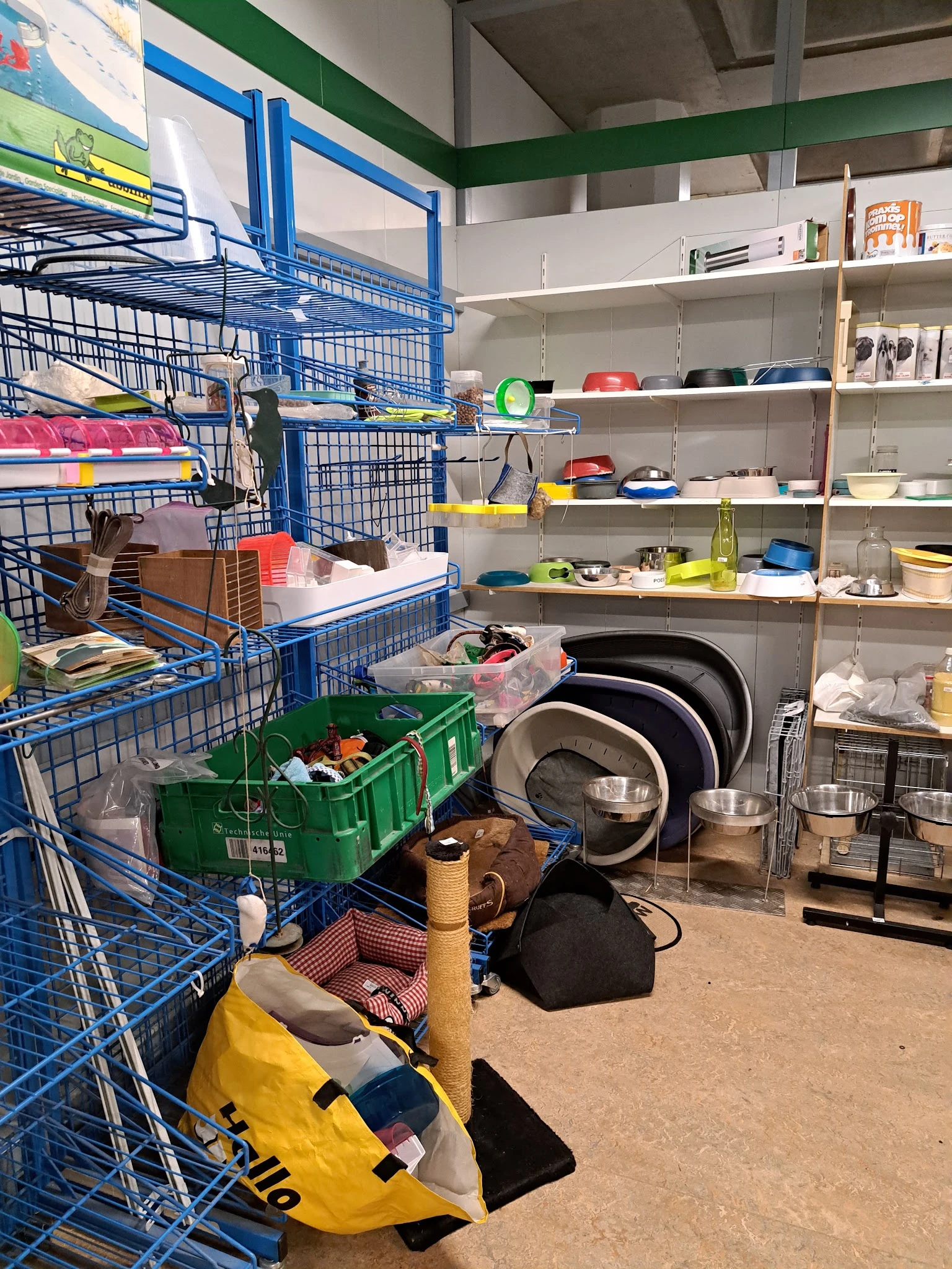Stellingen met huishoudelijke artikelen, pannen, servies, dozen met spullen en blauwe opbergkratten in de winkel