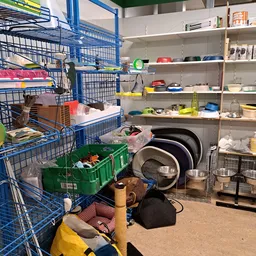 Stellingen met huishoudelijke artikelen, pannen, servies, dozen met spullen en blauwe opbergkratten in de winkel