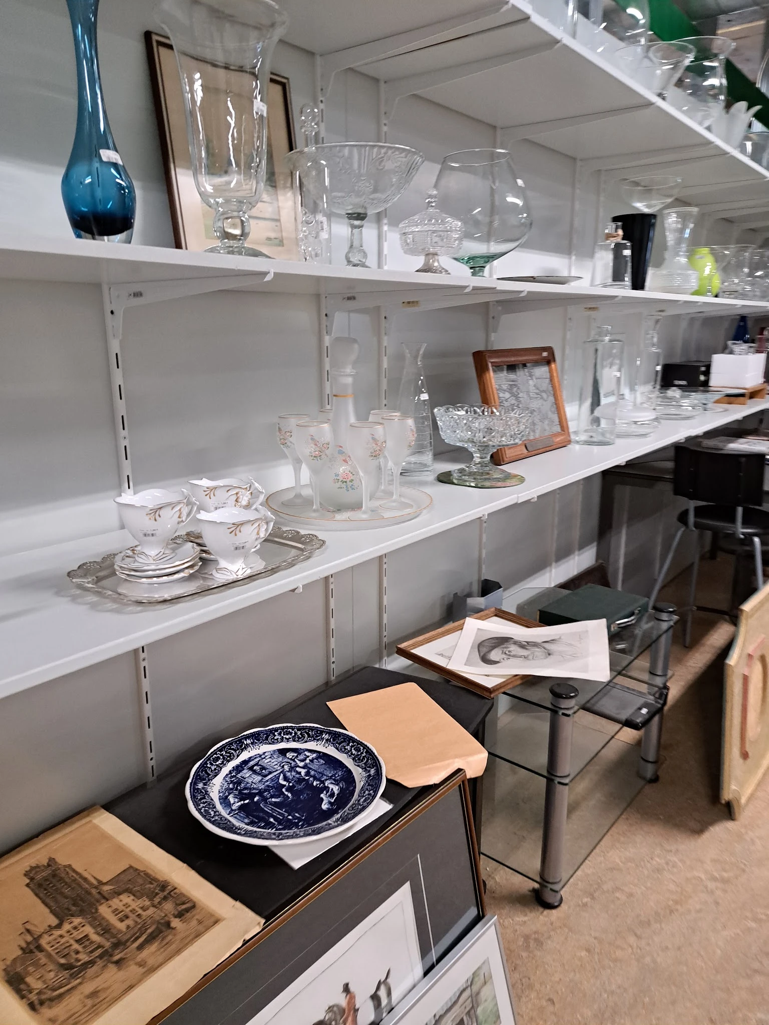 Witte wandkasten met servies, glazen en decoratieve items zoals kopjes, kannen en kristal