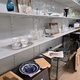 Witte wandkasten met servies, glazen en decoratieve items zoals kopjes, kannen en kristal