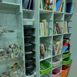 Witte stellingen met boeken, zwarte opbergboxen en groene bakken in kringloopwinkel