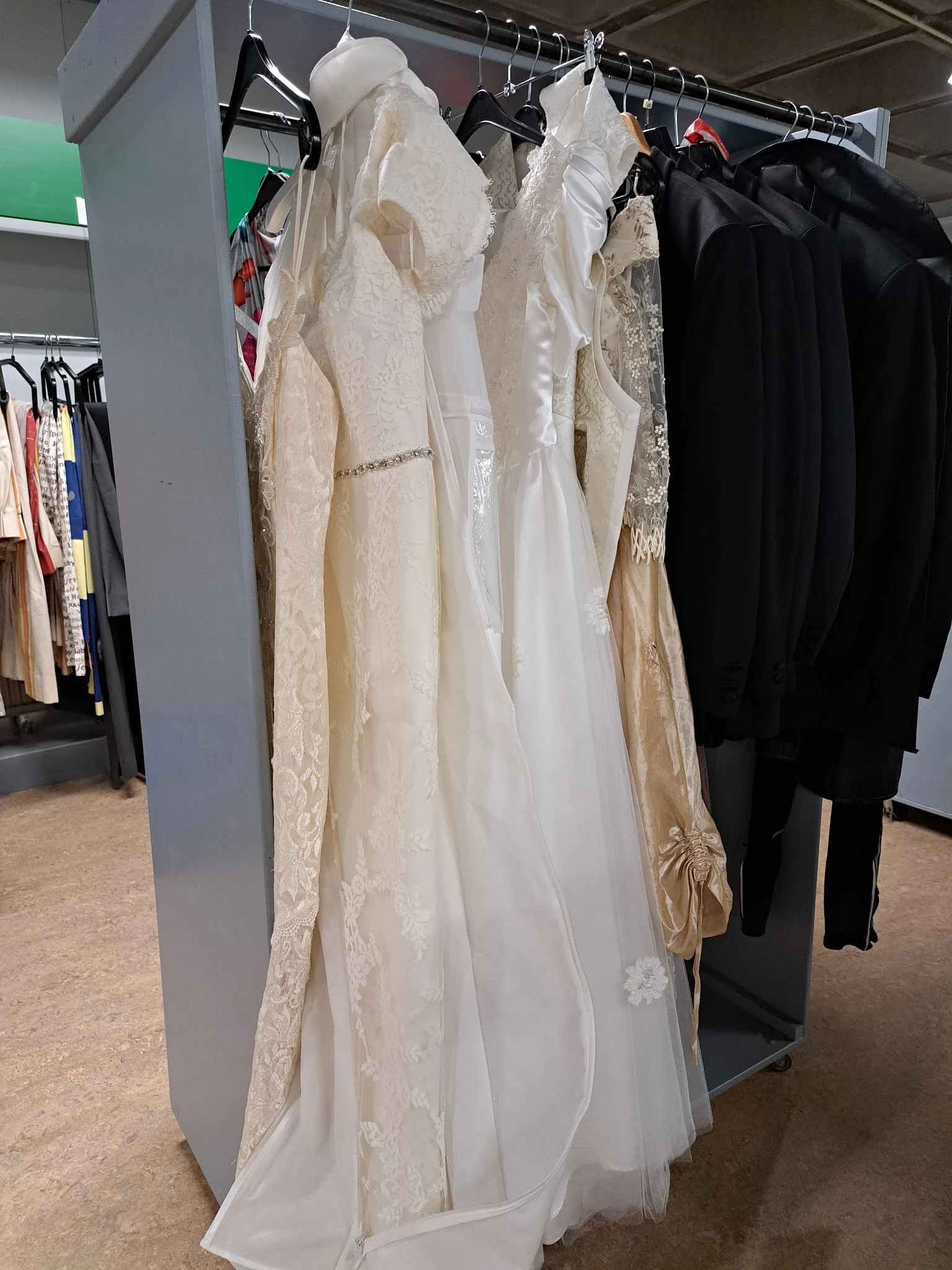 Rekken met tweedehands bruids- en feestkleding in crème en ivoor tinten