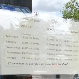 Openingstijden op een wit papiertje geplakt op een raam