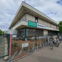 Voorgevel van kringloopwinkel Pelgrimshoeve met groene winkelnaambord, fietsenstalling met fietsen, en aangeven van Wattstraa