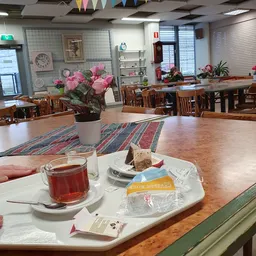 Tafel in lunchroom met kopje thee, gebak en bloemen in pot