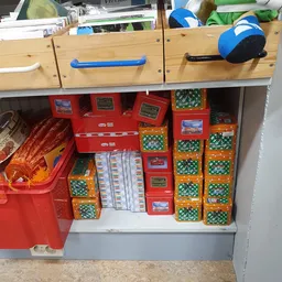 Opbergkast met rode en groene opbergboxen, oranje jas en verschillende dozen met spullen