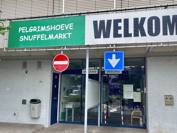 Winkelgevel met groene en witte borden, donkerblauwe deuren en 'Welkom' opschrift