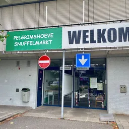 Winkelgevel met groene en witte borden, donkerblauwe deuren en 'Welkom' opschrift