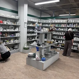 Winkelvloer met centrale displaytafel en stellingen vol serviesgoed en huishoudartikel