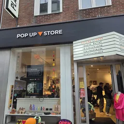 Gevel van Pop Up Store met zwart winkelfront, grote glazen ramen met uitgestalde kleding en een bordje 'Secondhand' aan de zi