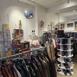 Winkelinterieur met kledingrekken, schoenen op displays en accessoires, disco ball aan plafond