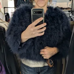 Selfie van persoon in zwarte bontjas met smartphone
