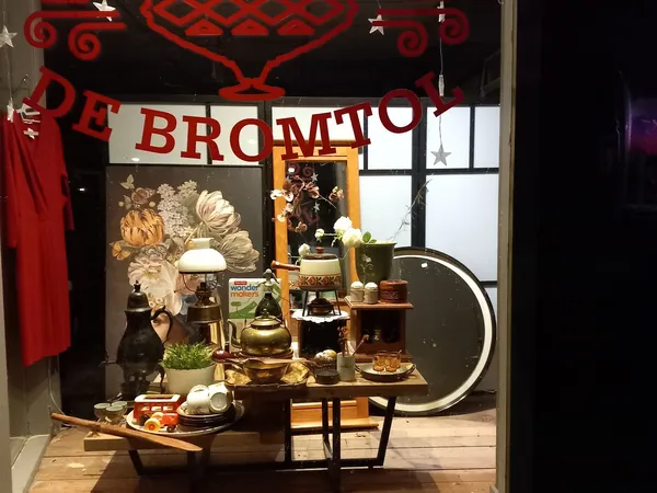 Winkelraam met sfeervolle display van huishoudartikelen, decoratie en plantenplanten tegen donkere achtergrond