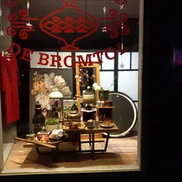 Ingerichte etalage met decoratie, bloemen, meubels en accessoires in warme tinten met rood accent