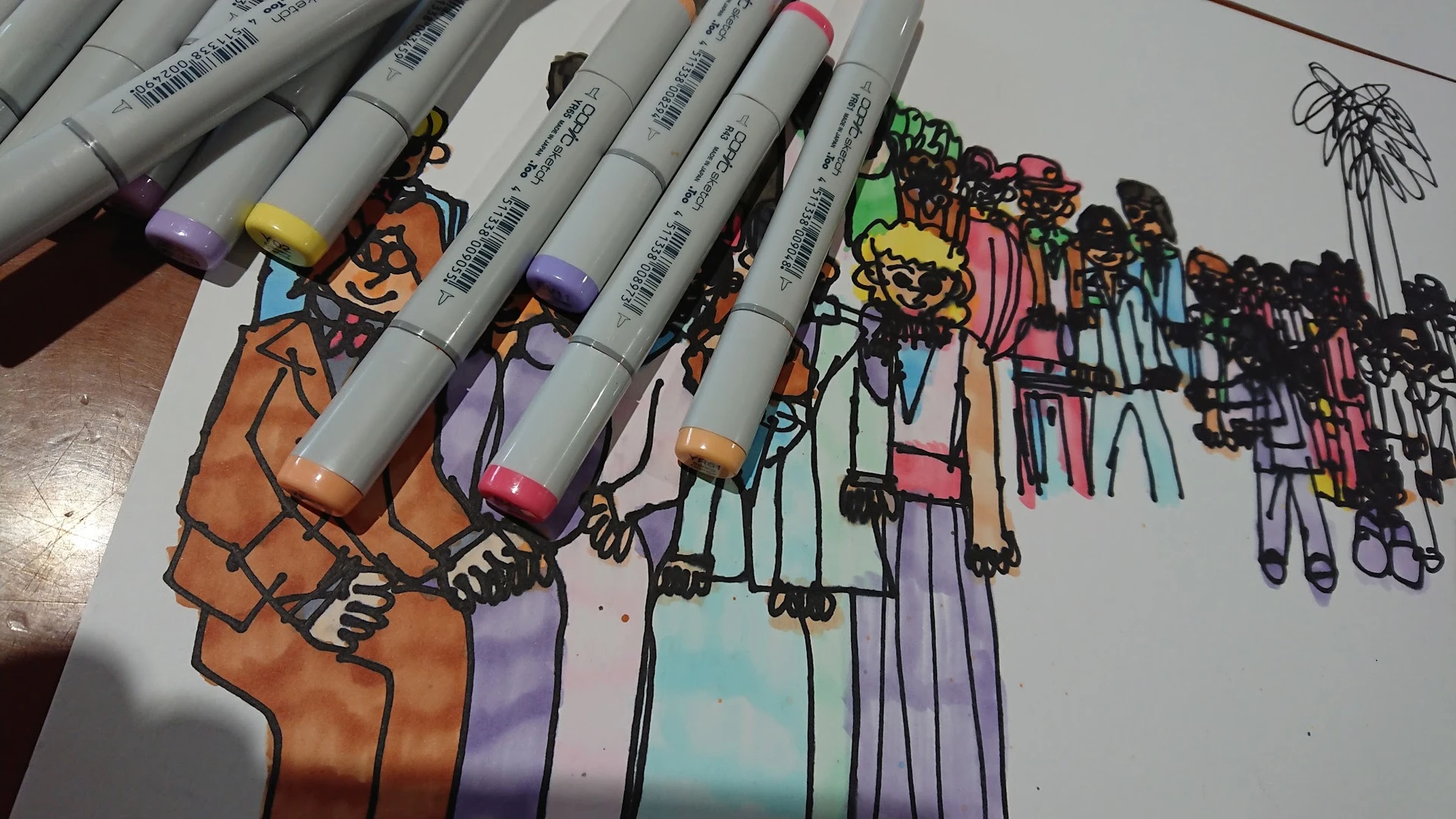 Close-up van gekleurde markers/stiften naast een kleurrijke handgetekende illustratie met figuren