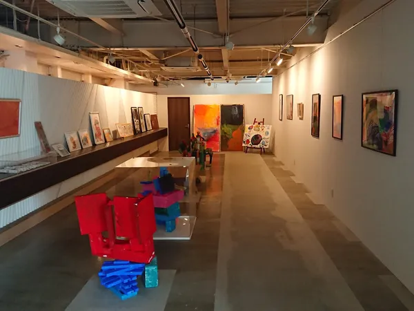 Winkelvloer met kunststukken en rode sculpturen, tentoonstellingsachtige opstelling met verlichte wanden