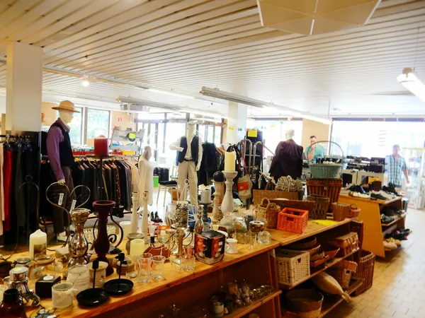 Winkelvloer met toonbanken, uitgestalde artikelen, kleding op rekken en mannequins in een kringloopwinkel