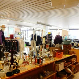 Winkelvloer met toonbanken, uitgestalde artikelen, kleding op rekken en mannequins in een kringloopwinkel