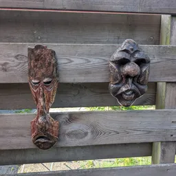 Twee houten decoratieve gezichtsmaskers bevestigd aan houten planken