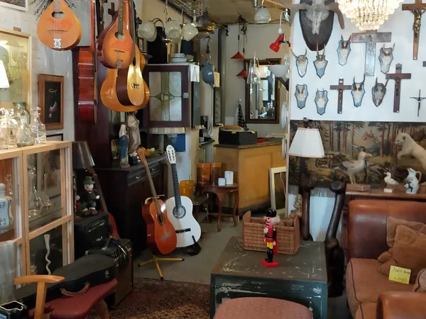Winkelinterieur met muziekinstrumenten, religieuze artikelen en diverse spullen aan muren en vloer