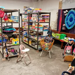 Winkelvloer met stellingen vol speelgoed, spellen en kinderartikelen in een kringloopwinkel