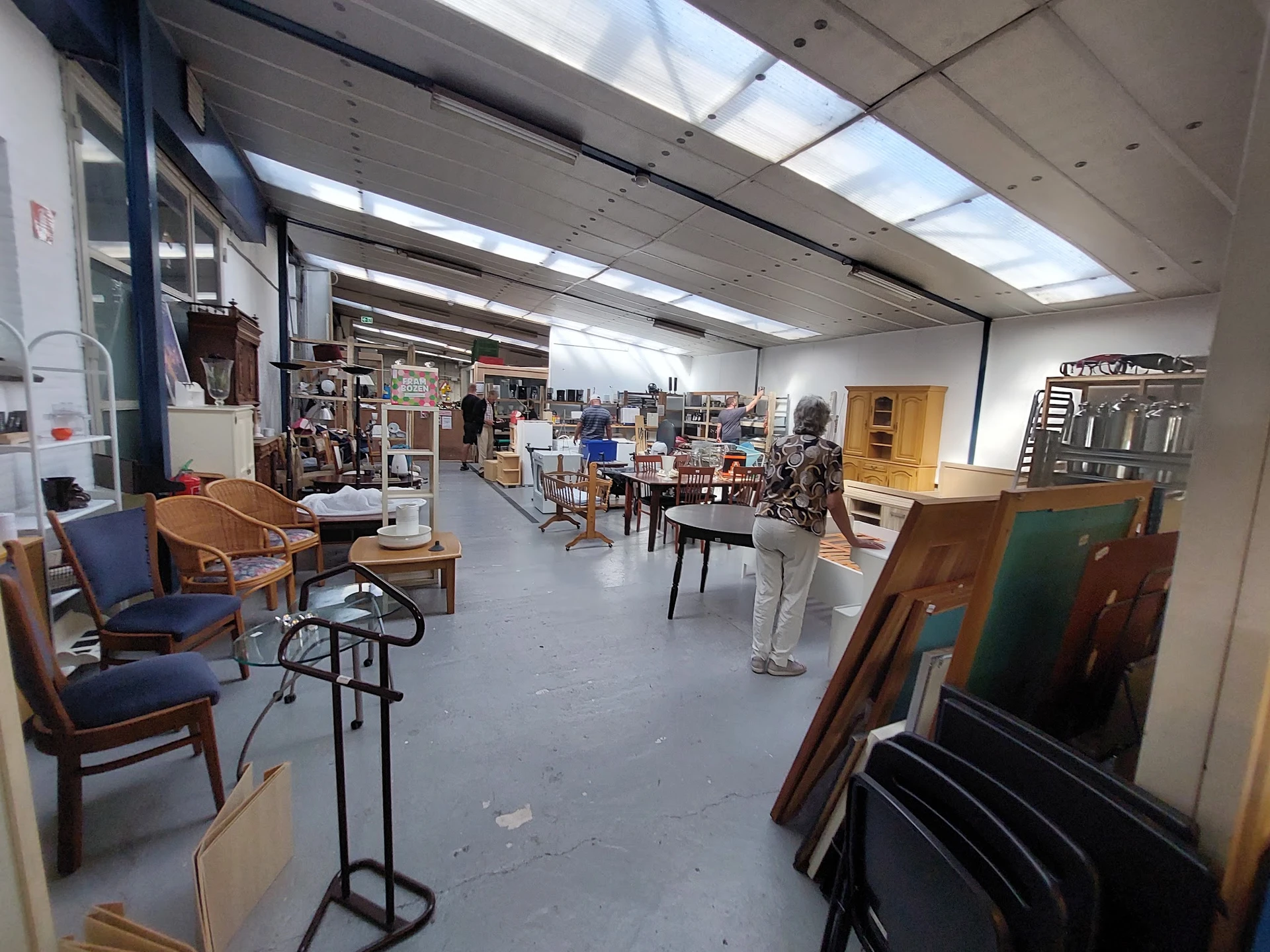 Ruim interieur van kringloopwinkel met diverse meubels, stoelen en huishoudelijke spullen uitgestald