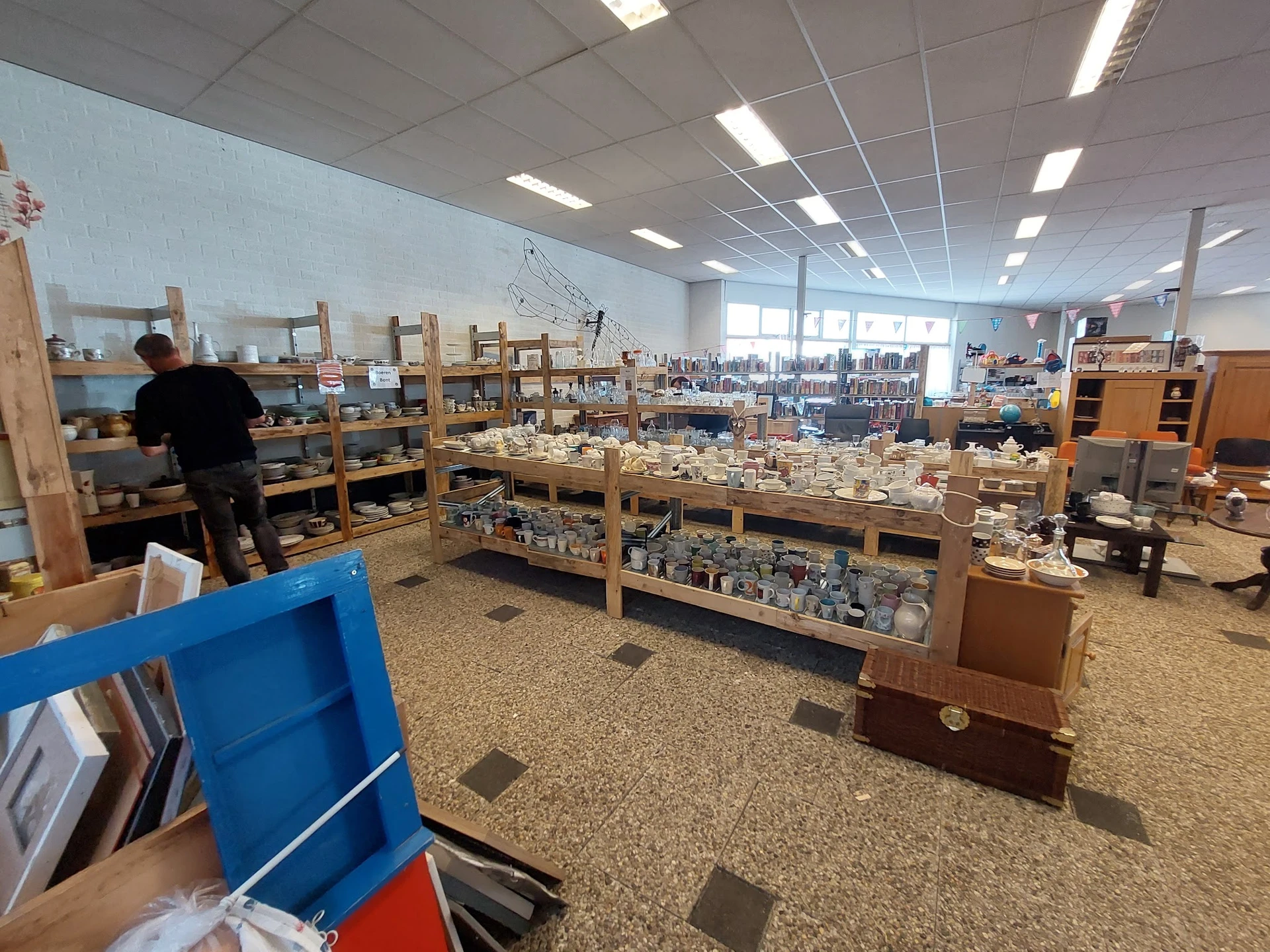 Winkelvloer met houten stellingen vol serviesgoed en huishoudelijke artikelen