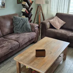 Woonkamer met twee bruine zitbanken, houten salontafel en diverse meubels en decoratie