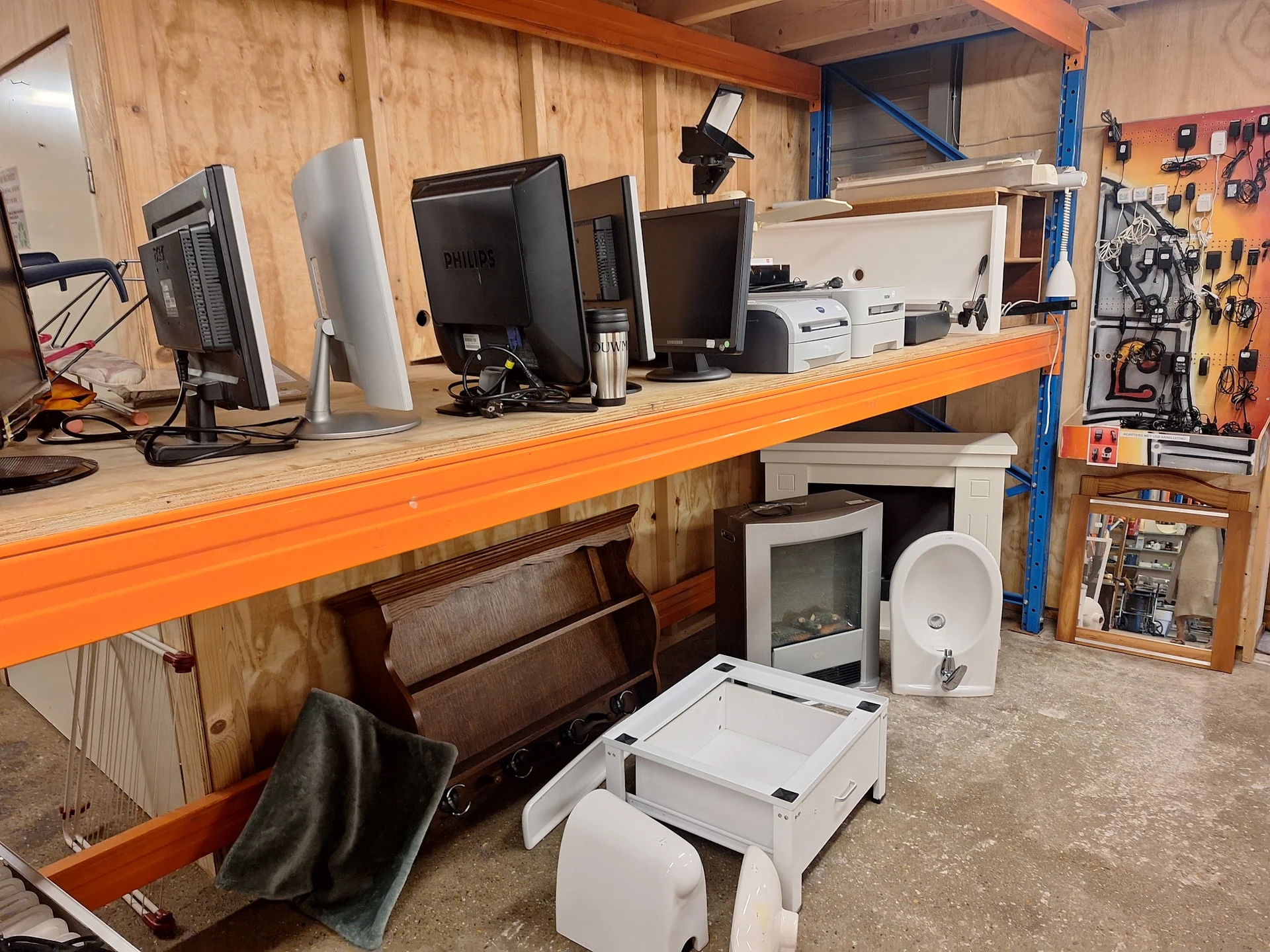 Werkplaats met oranje werkbank, computers, printers en gereedschapskast met tools