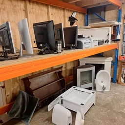 Werkplaats met oranje werkbank, computers, printers en gereedschapskast met tools