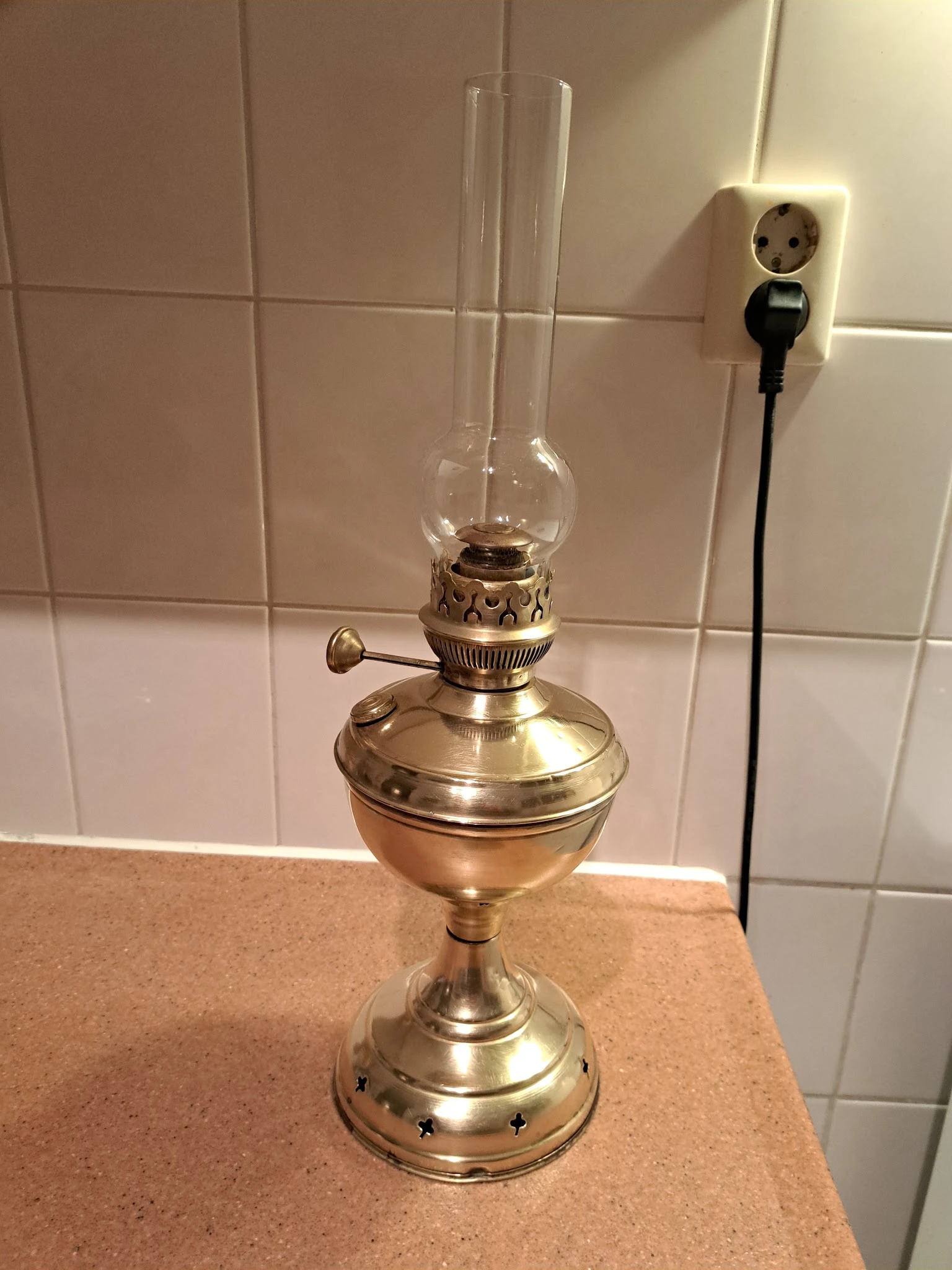 Antieke bronzen olielamp met glazen lampenkap op tegelmuur achtergrond