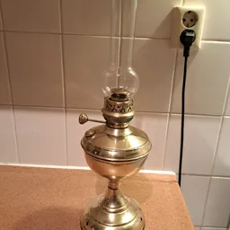Antieke bronzen olielamp met glazen lampenkap op tegelmuur achtergrond