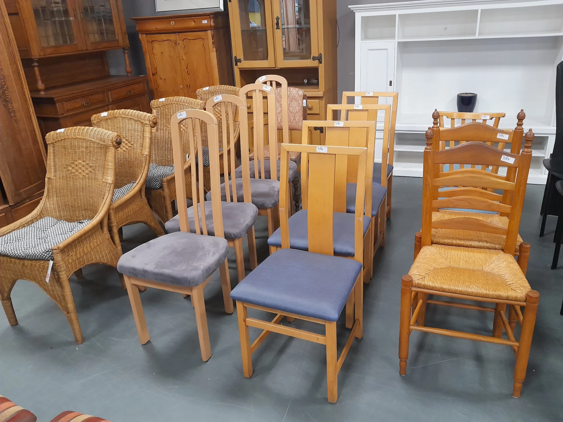 Diverse houten stoelen en fauteuils met verschillende stijlen en afwerkingen uitgestald in de winkel