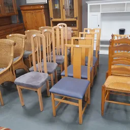 Diverse houten stoelen en fauteuils met verschillende stijlen en afwerkingen uitgestald in de winkel