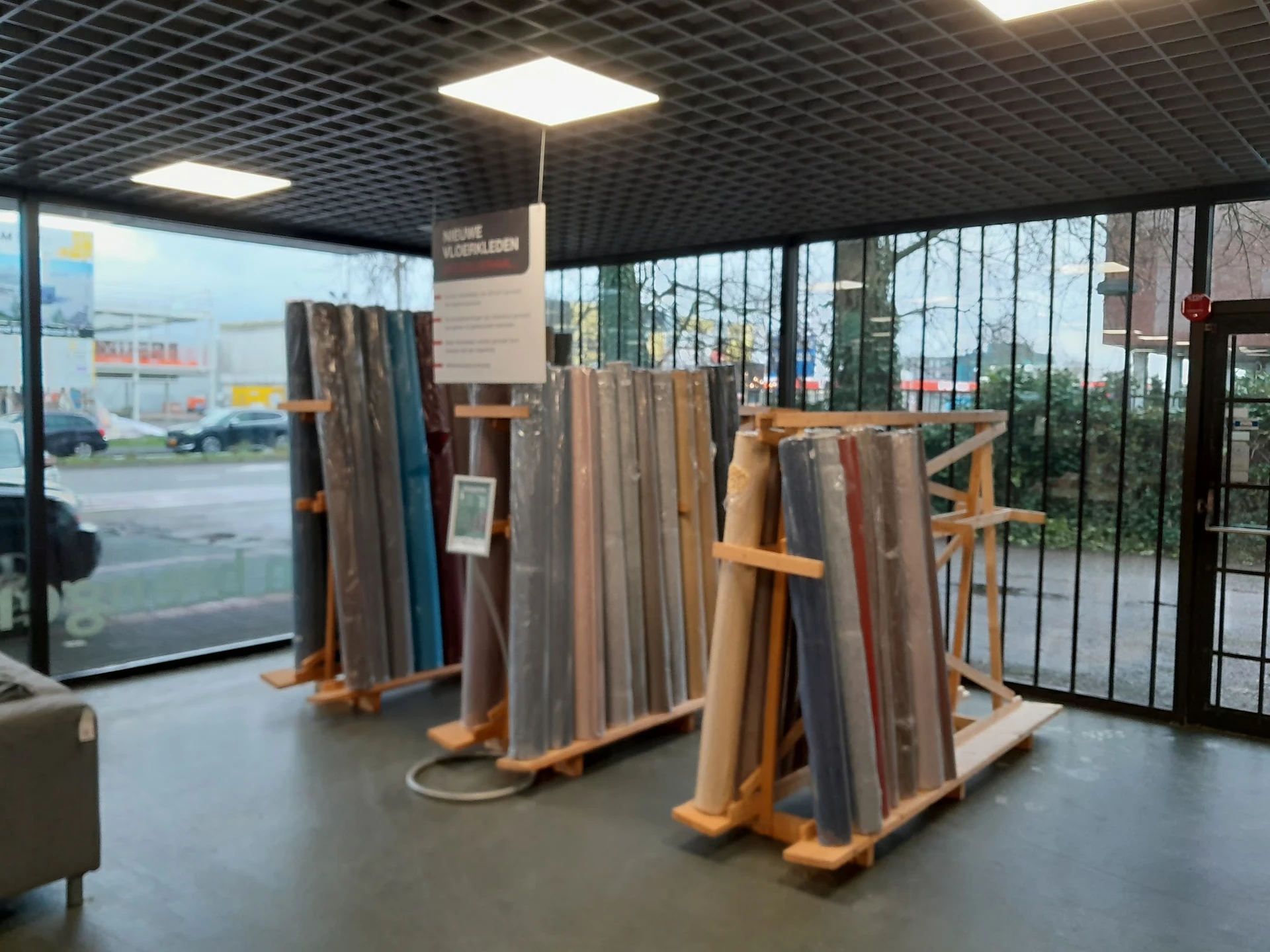 Houten stellingen met uitgestalde tapijten en vloerbekleding in verschillende kleuren en patronen