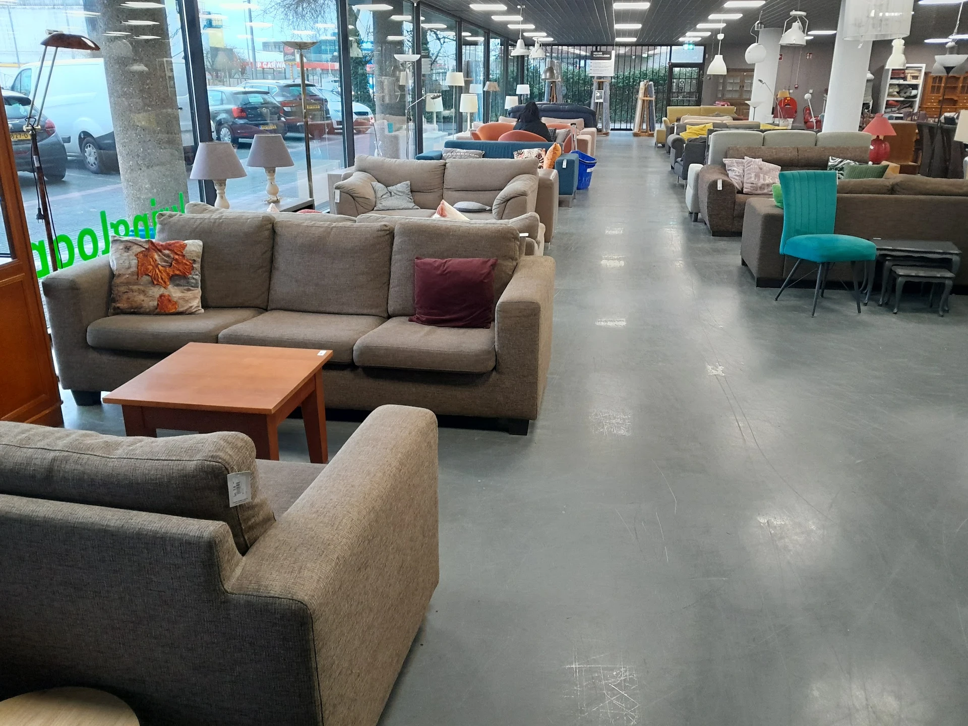 Winkelvloer met uitgestalde meubels: zithoeken, banken en fauteuils in verschillende kleuren, helder verlicht interieur