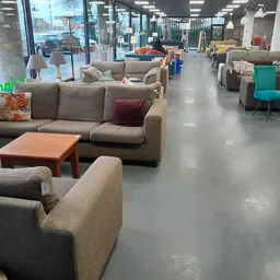 Winkelvloer met uitgestalde meubels: zithoeken, banken en fauteuils in verschillende kleuren, helder verlicht interieur